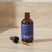Agen Hair Oil — open bottle with dropper and oil drop on a stone counter