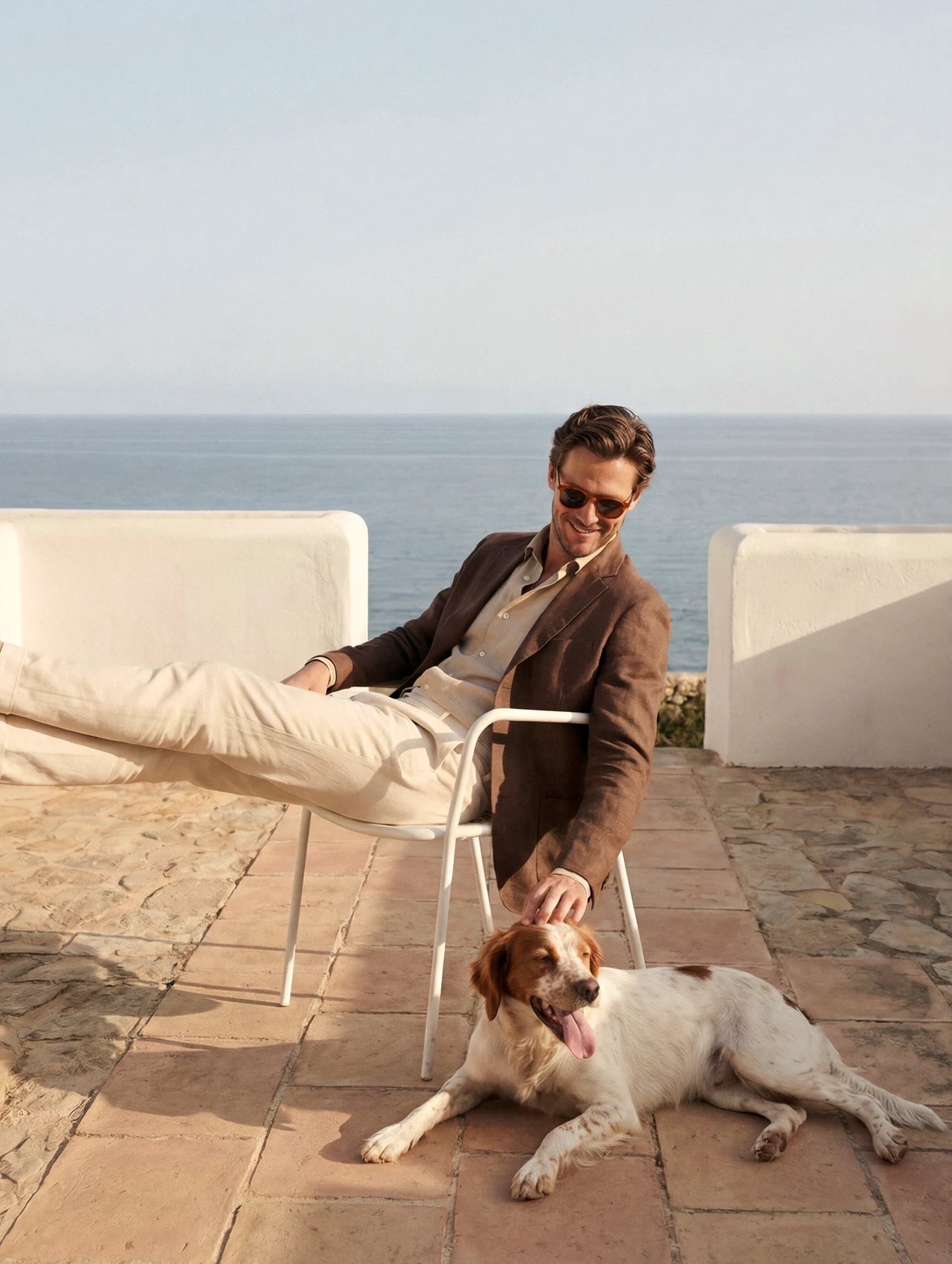 Relaxed man in the sun on a seaside terrace, dog at his feet