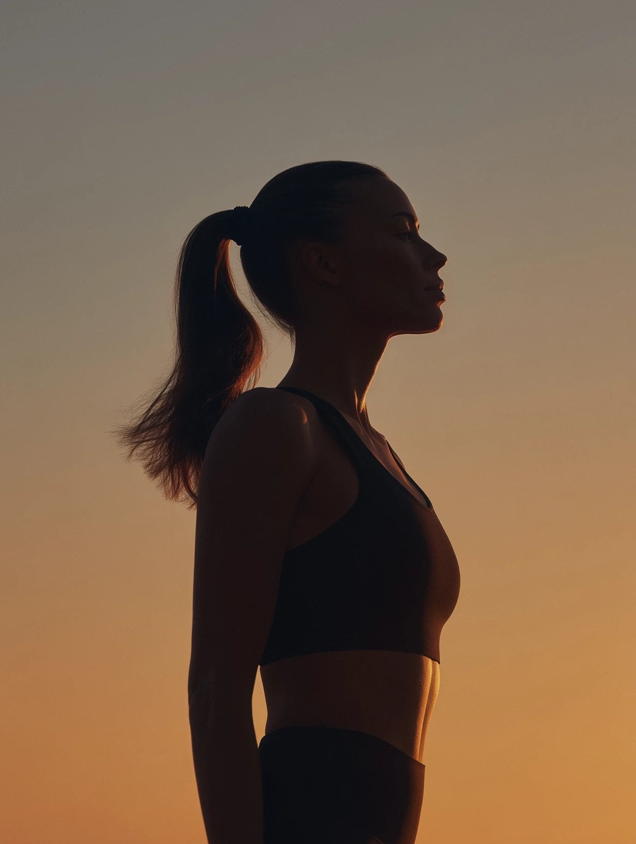 Woman in profile at sunset, silhouetted against a warm sky